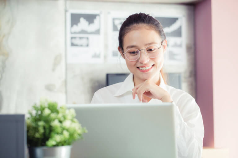 Young asian woman smiling at a laptop screen