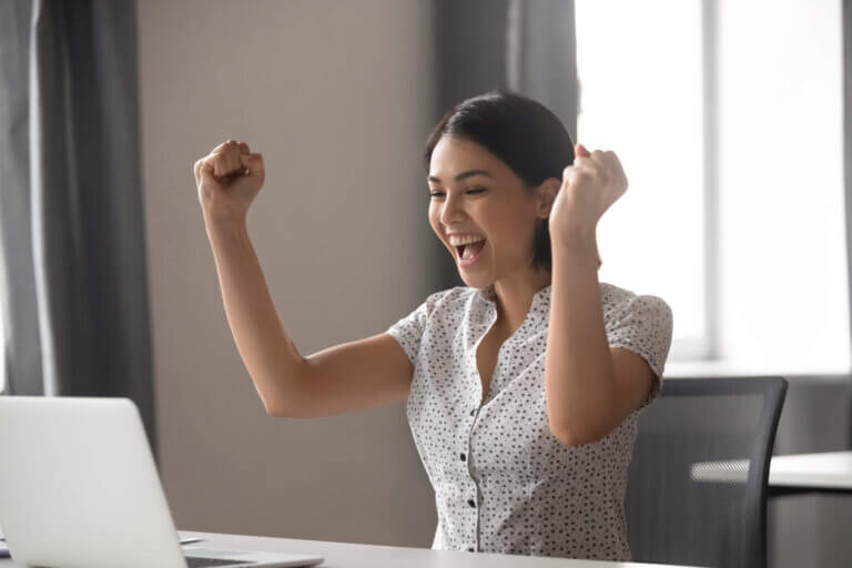 Woman in front of laptop, rejoicing about landing a dream job in the Philippines.