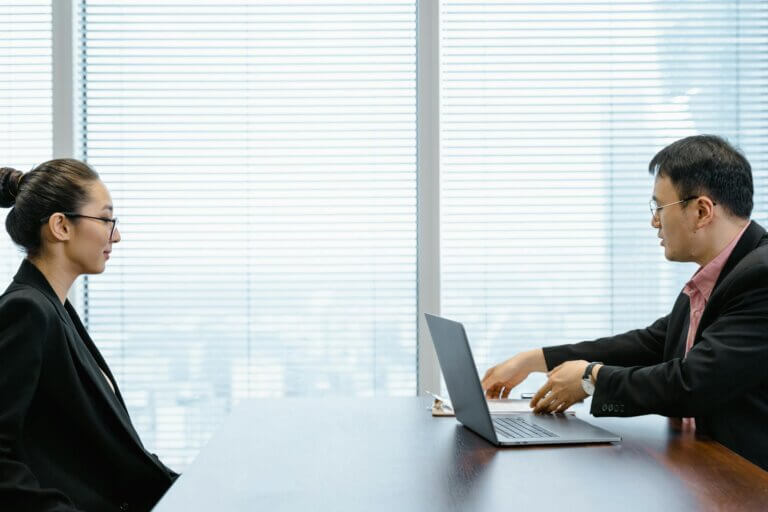 Woman Sitting in Front of Man at Table with Laptop