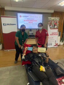 person donating blood with two people assisting 