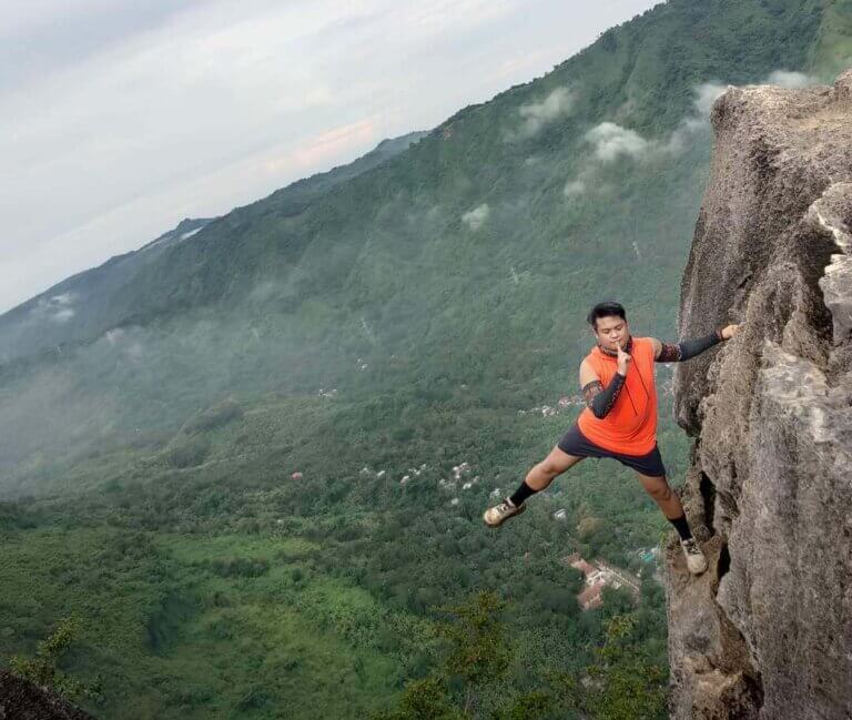 man holding onto the side of a mountain, employee mental health concept