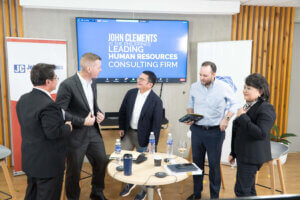 five people standing around a small table talking 