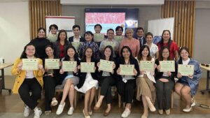 a small group of people posing for a photo with women sitting upfront, holding up certificates 