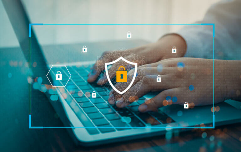 person typing on a laptop with padlock and shield icon; cybersecurity concept