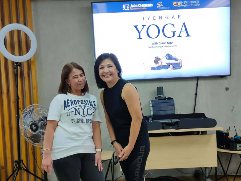 two females in posing for a photo in front of a screen that says "Iyengar Yoga"