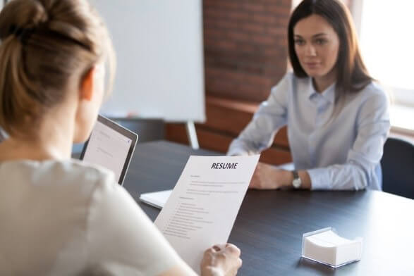 Two women in a professional setting during a job interview, with one reviewing the other's resume. This image represents job opportunities in the Philippines, focusing on career advancement and recruitment.