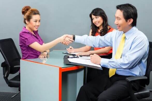 Job candidate shaking hands with interviewers, demonstrating how to ace job interviews through confidence and building rapport.