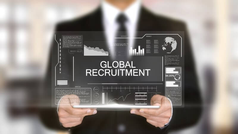 A business professional holding a virtual screen displaying global recruitment data, representing overseas recruitment processes.