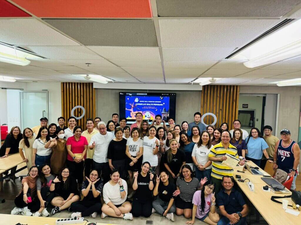 A large group of employees smiling and posing together after participating in an event that focused on workplace health programs.