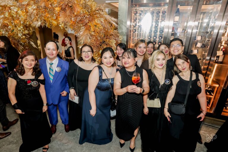 Attendees at the John Clements Consultants 50th Anniversary, posing under elegant gold decor and celebrating a milestone evening.