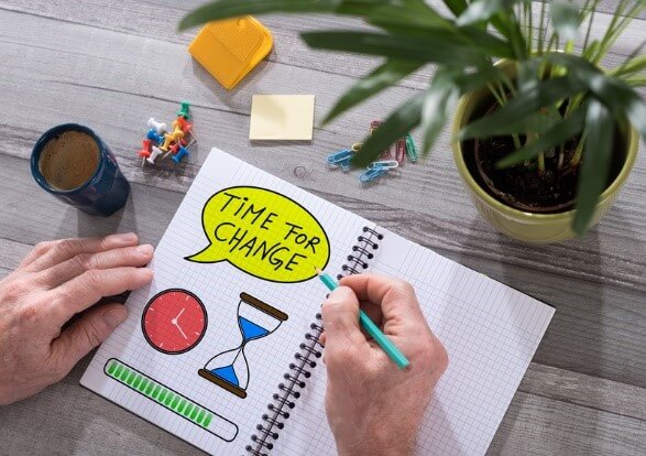 Notebook with colorful illustrations and the text 'Time for Change,' symbolizing career change tips, placed on a desk with a coffee cup, plant, and office supplies.