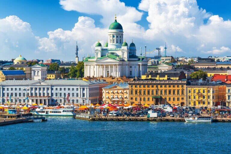 Scenic view of Helsinki, Finland, featuring the Helsinki Cathedral, vibrant waterfront buildings, and a bustling marketplace, perfect for showcasing a corporate trip to Finland.