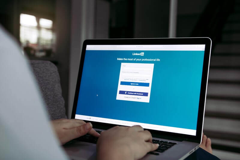 Person using a laptop to access the LinkedIn login page, focusing on creating an optimized LinkedIn profile.