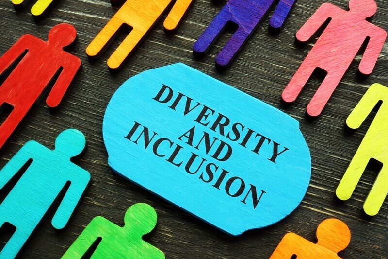 A sign reading "Diversity and Inclusion" is surrounded by colorful human-shaped cutouts, symbolizing diversity and inclusion in recruitment.