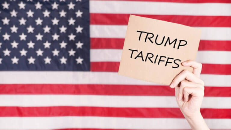 Hand holding a sign that reads 'Trump Tariffs' against a backdrop of the U.S. flag, representing the impact of U.S. trade policies on Philippine manufacturers.