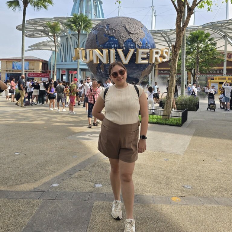 A traveler poses in front of the Universal Studios globe at Sentosa, Singapore, a popular destination featured in many Singapore travel guides.