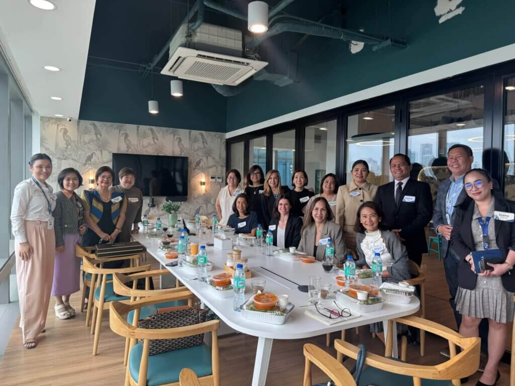 A group of women leaders in the Philippines posing together for a photo at a long table during a formal event.