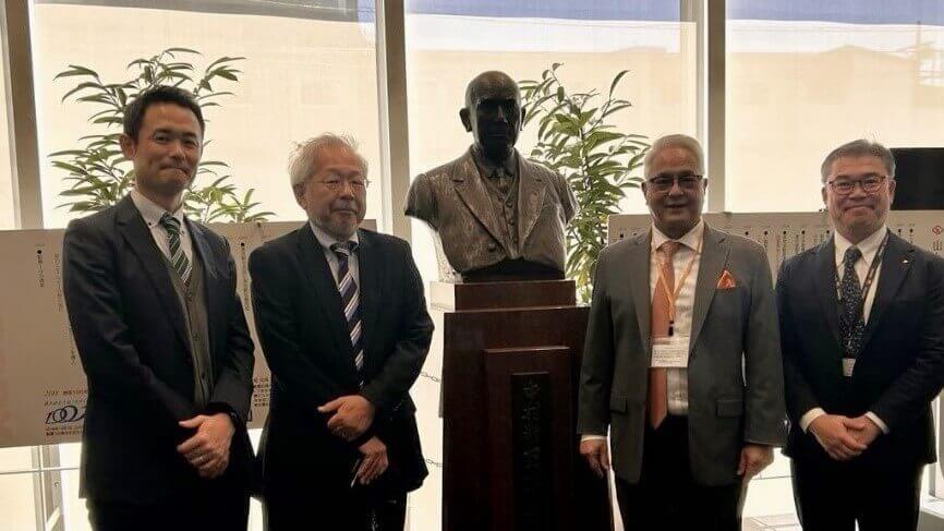 Four professionals pose beside a statue during a business trip to Japan for client engagement, highlighting cross-cultural partnership and collaboration.