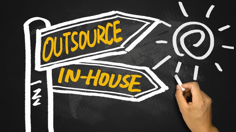 Chalkboard illustration showing a signpost with two arrows labeled "Outsource" and "In-House," representing the decision between in-house recruitment vs recruitment consultancy.