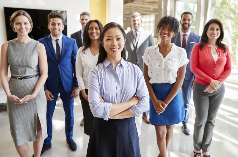 A diverse group of professional women and men standing confidently in a modern office, symbolizing empowerment and the importance of upskilling women in the digital age.